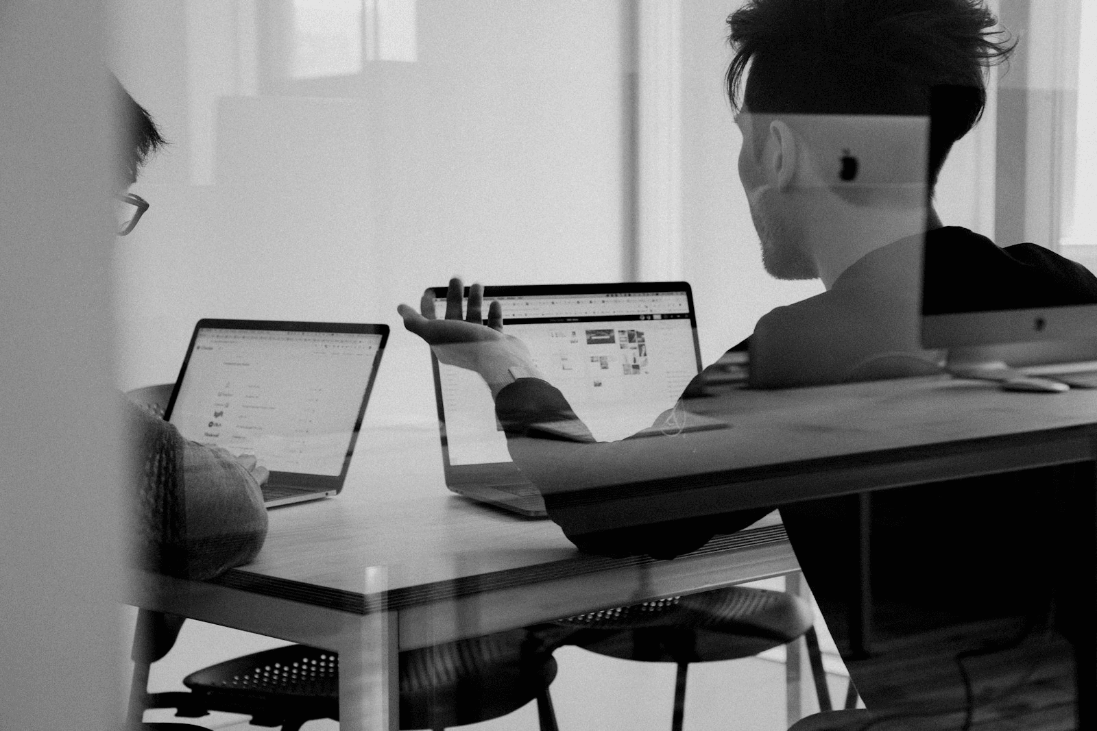 Engineers pair-programming at a shared workstation in a modern office